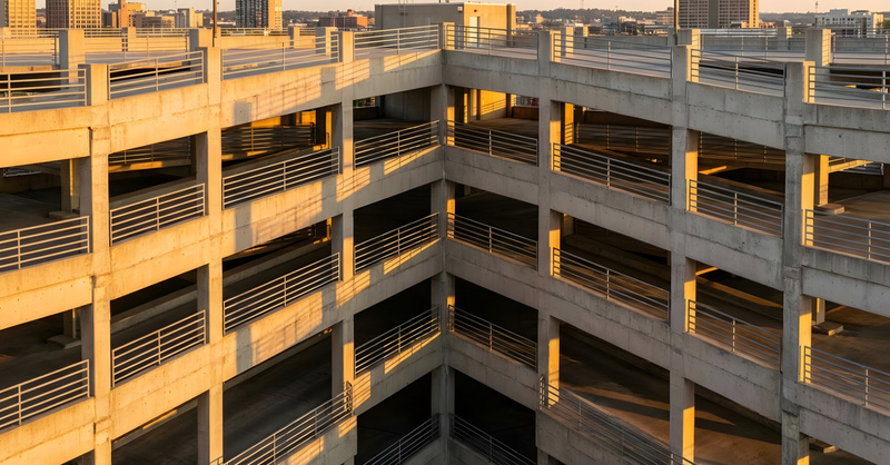 Multilevel concrete parking structure with a city skyline in the background.