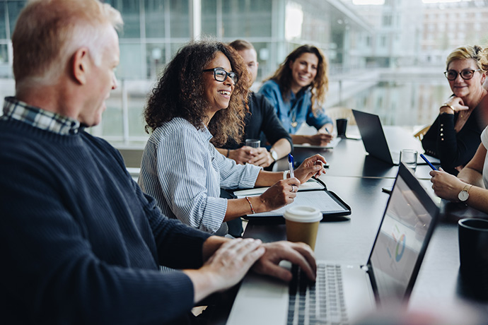 smiling coworkers sitting around a conference room table