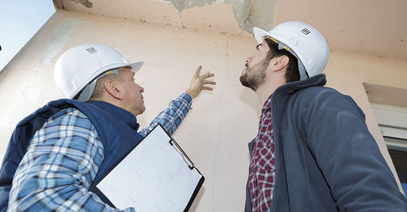 Male builder inspecting roof damage