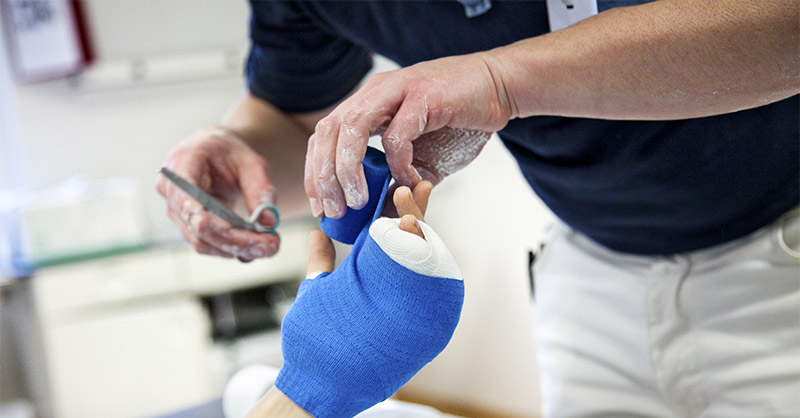 Doctor applying cast to patience in hospital bed