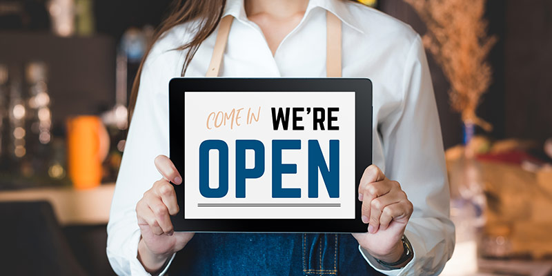 Business owner holding an open for business sign
