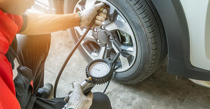 Mechanic checking tire pressure on car