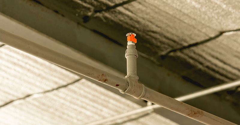 Closeup of one sprinkler head of an automatic fire sprinkler system installed at the ceiling of a building currently under construction