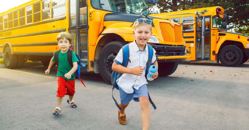Two boys running off of school bus