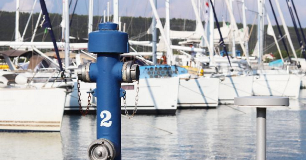 Fire‑fighting crane on a marina dock with sailboats in the background, representing marina fire safety, emergency preparedness, and fire prevention measures to protect boats, guests, and waterfront property.
