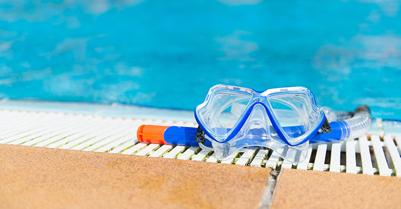 A snorkel mask on the edge of a swimming pool