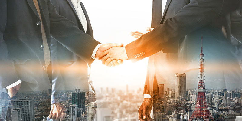 businessmen shaking hands on an overlay of a cityscape