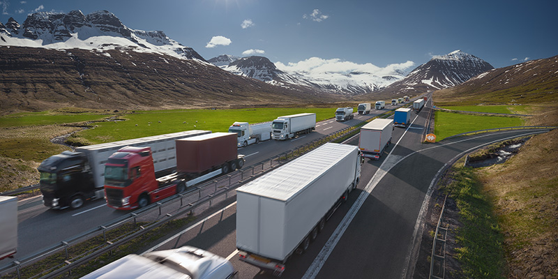 cargo trucks driving on highway route through mountains