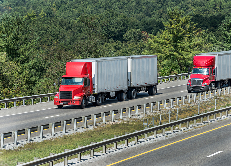 Two Red Semi Trucks On The Interstate