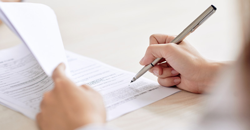 Hand and pen filling out paper form